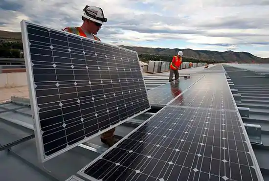 two workers in orange safety vests installing solar panels
