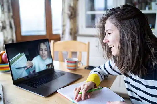 Smiling girl watching online tutor on laptop