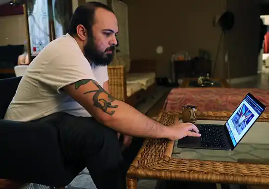 man with tattoo searching on laptop