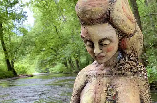 stylized statue of woman in the river with look what I found carved on the chest