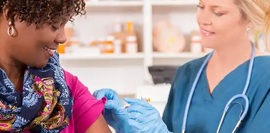 female doctor giving flue shot to afroamerican women ,both smiling 