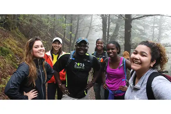 5 women and one man on hiking trail in misty woods