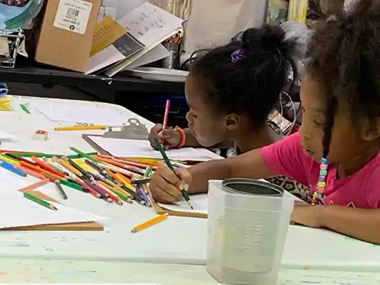 2 young afroamerican girls drawing with pencils