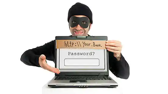 hacker in black mask pointing to laptop