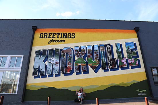 woman with child under Greetings from knoxville mural