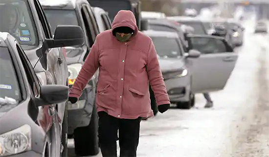 woman walking by parked cars on snowy street
